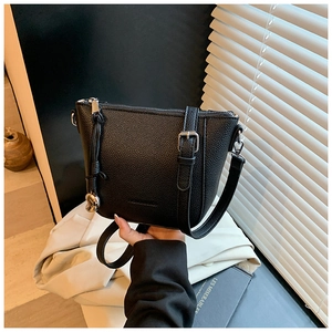 Détail du sac seau noir en cuir grainé avec boucle argentée et pendentif sphérique chic