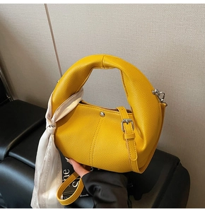 Detail der gelben Leder-Tasche mit Ringgriff und bedrucktem Seidenschal für Damen