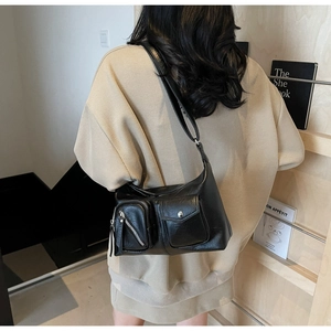Detail of black faux leather dumpling bag featuring utility pockets and silver hardware
