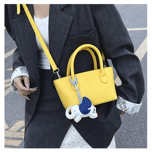 Macro detail of yellow leather bucket bag featuring pebbled texture and cute elephant charm