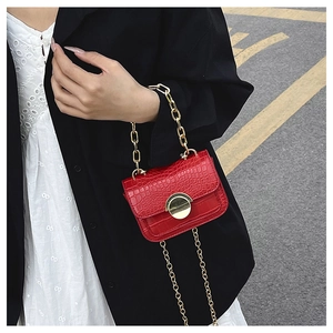 Detail of red croc-embossed girls crossbody bag with gold chain and heart metal clasp