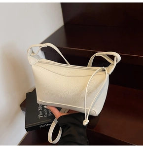 Close-up of white pebble grain leather handbag with adjustable strap and metal zipper