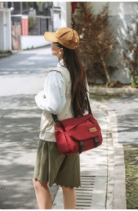 Close-up of red large capacity crossbody bag with buckle closure and side pocket details