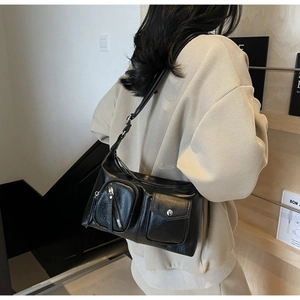 Close-up of black retro utility shoulder bag with silver zippers and buckle details