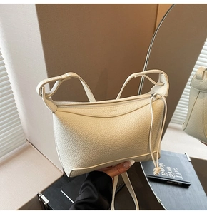 Close-up of cream-white litchi texture shoulder bag with zipper and fringe detail