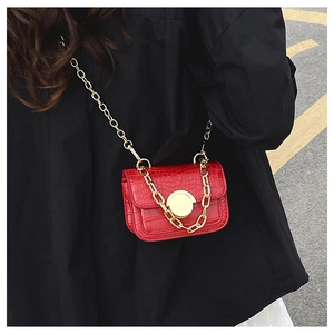 Detail of red croc-embossed mini bag featuring a gold chain strap and metal lock