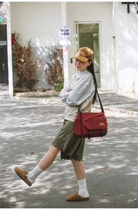 Detail of red canvas messenger bag with flap closure and dual buckles for daily use