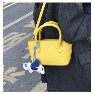 Detail of yellow pebbled leather mini bucket bag with a cute elephant charm pendant