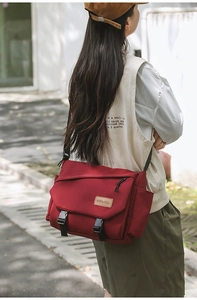 Outdoor shot showing the large capacity and adjustable strap of the burgundy messenger bag
