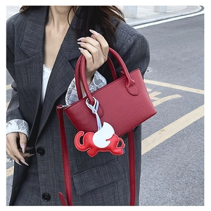 Detail of red pebbled leather tote bag with elephant charm on casual grey blazer outfit