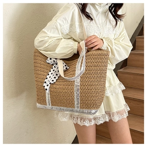 Détail d'un sac cabas en paille tissé main avec paillettes et nœud à pois