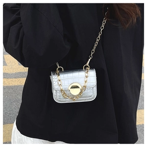 Detailed macro view of crocodile pattern texture on silver mini bag with gold chain strap