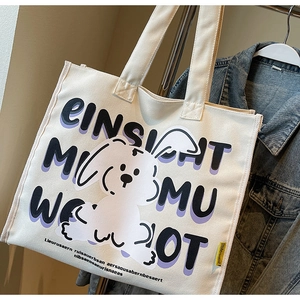 Detail of canvas tote bag featuring cute cartoon dog print and long shoulder strap