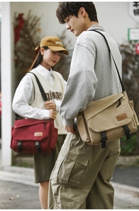 Outdoor street scene featuring large canvas messenger bags in khaki and deep red colors