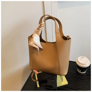 Detail of brown lychee grain bucket bag with silk scarf and gold HOCOMU logo