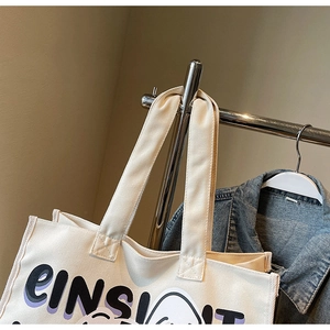 Detail of cream canvas tote bag showing purple letter print and street style graphic