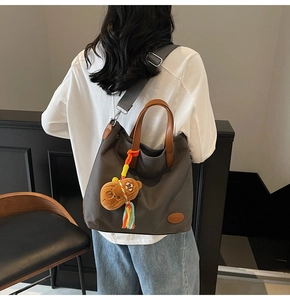 Detail of dark grey canvas tote bag with brown handles and a cute plush bear charm