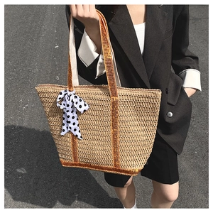 Détail d'un grand sac en paille tressée avec sangles jaunes et foulard à pois chic
