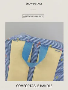 Detail view of the gingham plaid pattern and durable nylon handle on a school backpack
