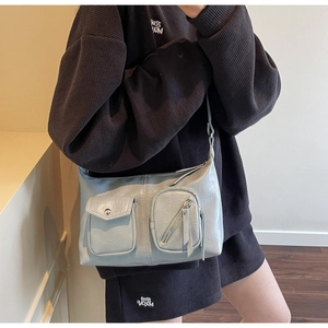 Detail view of light blue crossbody bag with double front pockets and long tassels