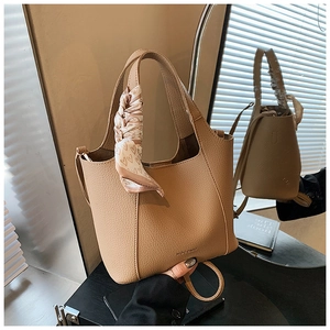 Detailed shot of camel lychee leather bucket bag with decorative heart print silk scarf