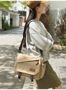 Detail of khaki canvas messenger bag featuring secure double buckle closure and side zipper pocket