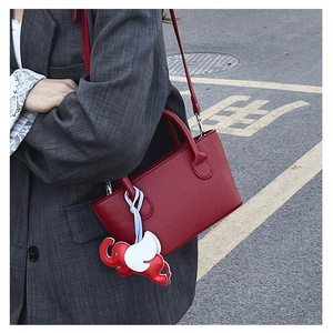 Detail of red leather bucket bag with litchi texture and cute elephant charm