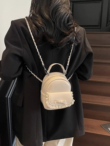 Chic cream mini backpack with lace and bow detailing shown on a model on stairs