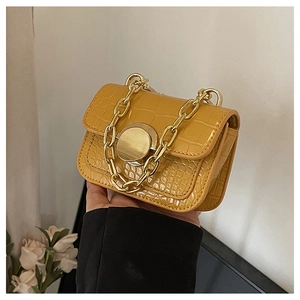 Close-up of yellow crocodile texture crossbody bag with gold chain strap and buckle