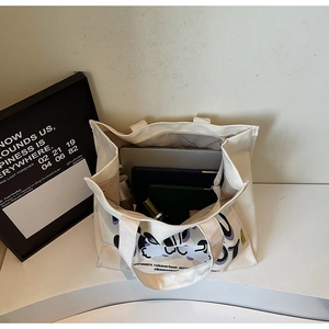 Interior view of white canvas tote bag showing large capacity for laptop and cosmetics
