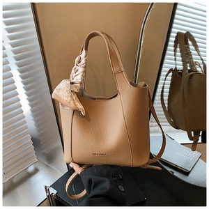 Detail of tan lychee leather bucket bag with silk heart scarf and MOCOMU logo