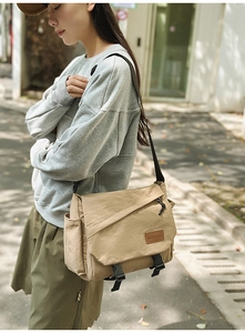 Khaki nylon messenger bag with adjustable strap and brand label shown on model
