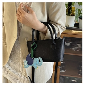 Detail of black lychee grain mini tote with blue elephant charm and round handles