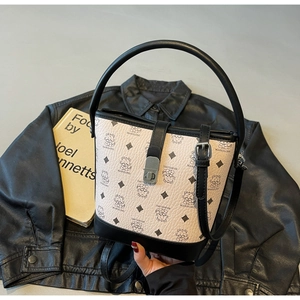 Detail of printed bucket bag with silver metal twist lock on black leather jacket background