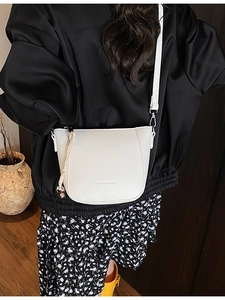 Sac seau blanc en cuir litchi avec bandoulière amovible porté par un mannequin
