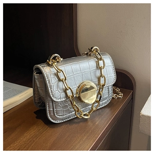 Detail of silver crocodile-patterned mini bag with gold chain and round metal lock