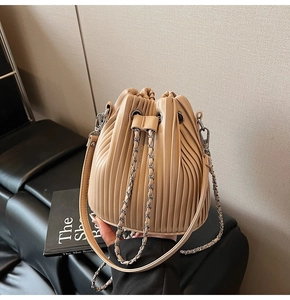 Detail showing vertical pleats on apricot bucket bag with silver metal drawstring chain