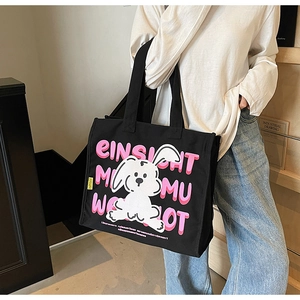 Detail of black canvas tote bag with pink artistic lettering and cartoon rabbit print