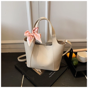 Beige lychee leather handbag detail with decorative pink heart scarf and logo