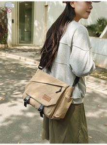 Outdoor shot of a man wearing a khaki canvas messenger bag with double buckles