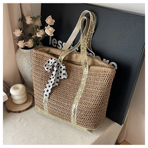 Détail du sac en paille avec bandoulières pailletées et nœud décoratif à pois