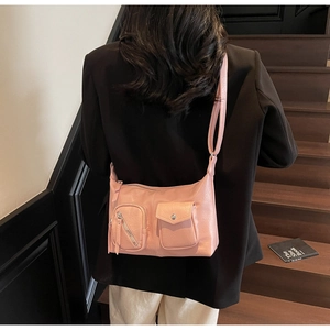 Detail of pink faux leather crossbody bag with multiple utility pockets and metal zippers