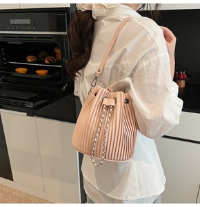 Pink pleated bucket bag with leather strap and silver chain shown in a lifestyle setting