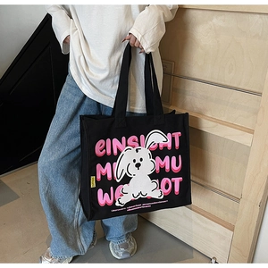 Detail of black canvas tote bag with cartoon rabbit print and pink artistic lettering