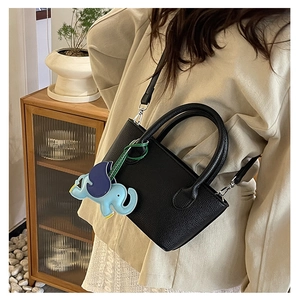 Detail view of black lychee grain leather bucket bag with cute elephant charm