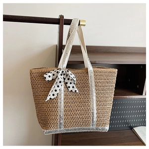 Détail du sac cabas en paille avec brides à paillettes argentées et nœud à pois noir