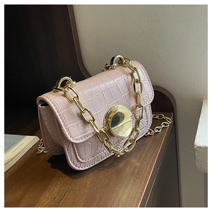 Detailed close-up of pink faux leather bag with crocodile texture and golden chain