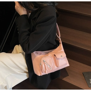 Pink multi-pocket faux leather shoulder bag with tassels shown on a model