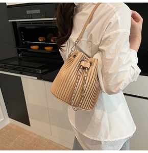 Detail view of beige pleated bucket bag with chain drawstring and premium texture