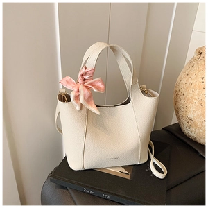 Close-up of cream lychee leather bucket bag with pink heart scarf and gold hardware